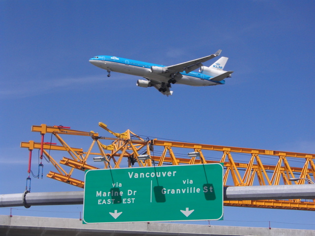 A KLM jet passes over as the Launching Truss walks across the South Arm Bridge. 
