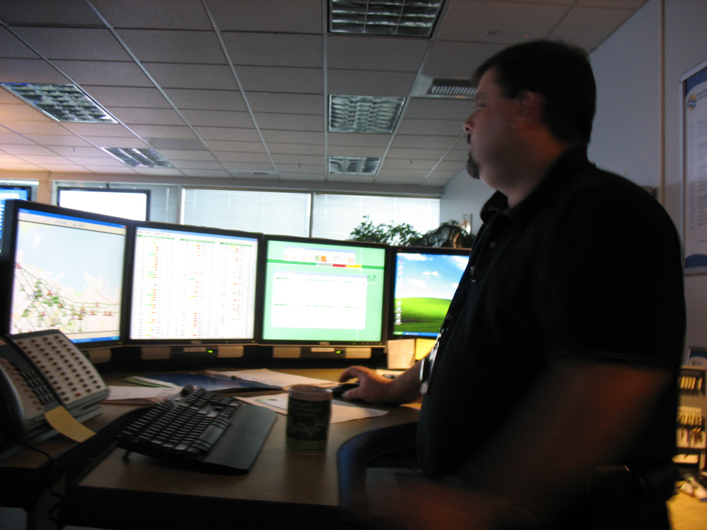 Duty manager Tony Madrid stands at the manager's desk, in the back of the T-Comm centre. Each supervisor has a row of screens like this displaying data from TMAC and more.