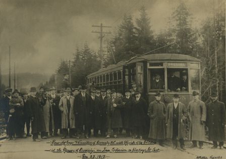 The opening of the Hastings Street Tramline Extension at Capitol Hill, Dec. 23, 1913. The 10,000-foot extension expanded a Vancouver streetcar route into Burnaby, from Boundary Road to Ellesmere Avenue. Joe Toffaletto wears the light-coloured coat near the photo’s centre: he headed the BCER construction team that built this line and also anchored the BCER tug-of-war team. Reeve McGregor of Burnaby is near the tram door, wearing a bow-tie and holding a pipe in one hand and a cane in the other, and Councillor Eber Stride is in front of the tram, in a three-piece suit with white shirt and bowler hat. The rest are unidentified, although other Burnaby councillors and BCER officials are said to be pictured. (Item 166-001, from the Burnaby Historical Society Community Archives Collection, courtesy of the City of Burnaby Archives.)