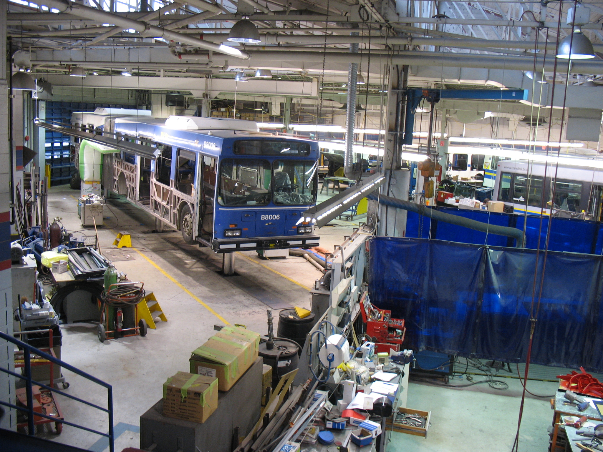 Another view of the articulated bus getting a mid-life overhaul. Notice that its lower body panels have been stripped off!