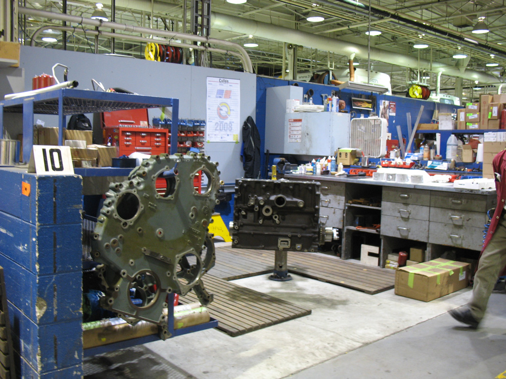 A mechanic’s bay for engine work, with engine block at centre. The blue shelf at left holds all the parts the mechanic might need for this particular part of engine. A mechanic’s bay for engine work, with engine block at centre. The blue shelf at left holds all the parts the mechanic might need for this particular part of engine.
