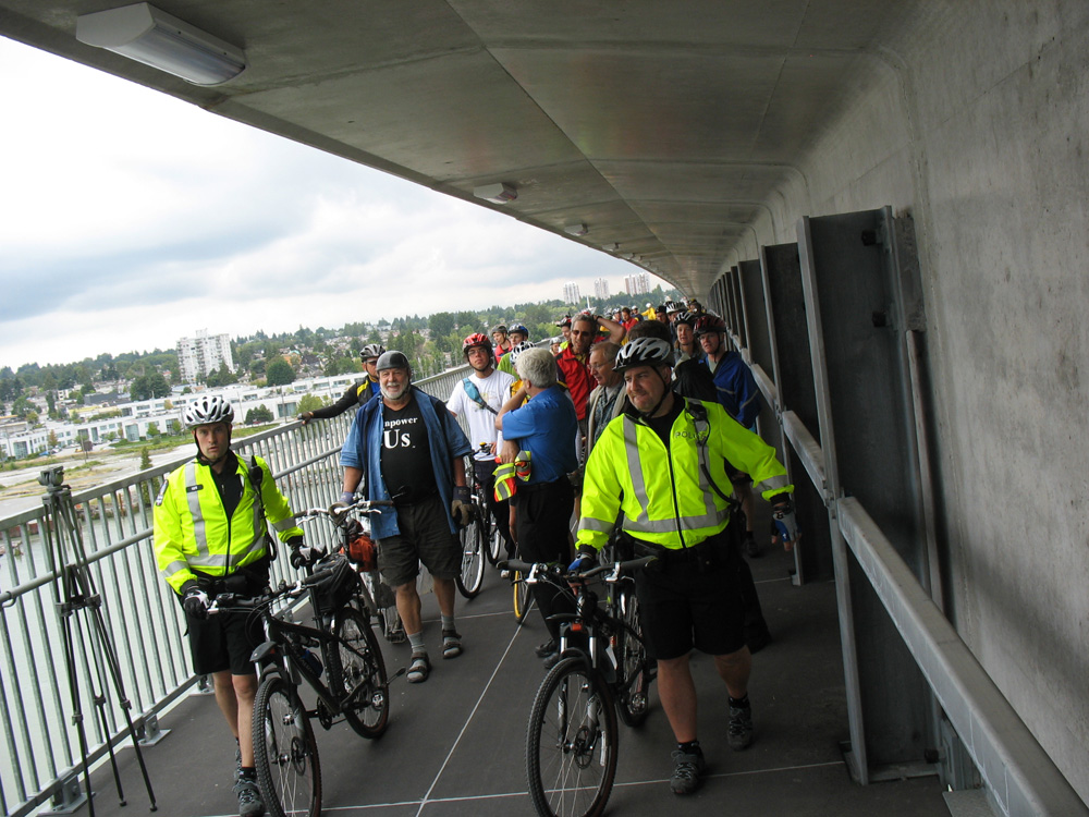 Led by the Transit Police, cyclists and pedestrians take a ceremonial first walk across the Canada Line bike and pedestrian bridge on its opening day.