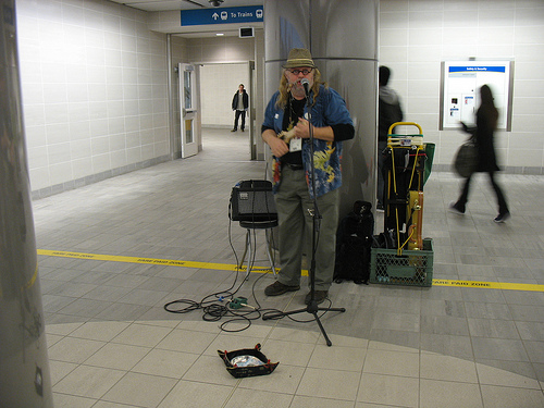 A busker next to the ticket machines at Waterfront Canada Line station.