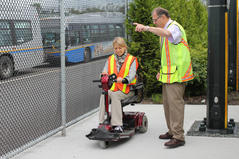Julie from Access Transit tries getting on transit with a scooter at Vancouver Transit Centre, under the guidance of trainer Bert.