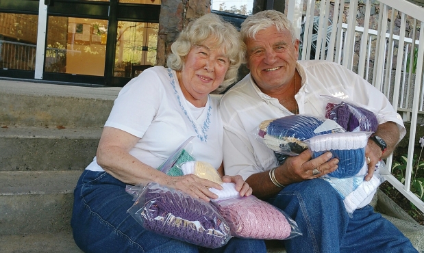 Joy Clapper and Bus Operator Glen Foster hold knitted items that will be donated to the Helping Hand charity