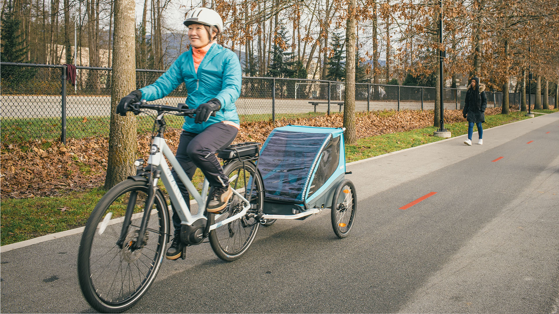 A person riding an e-bike with a trailer