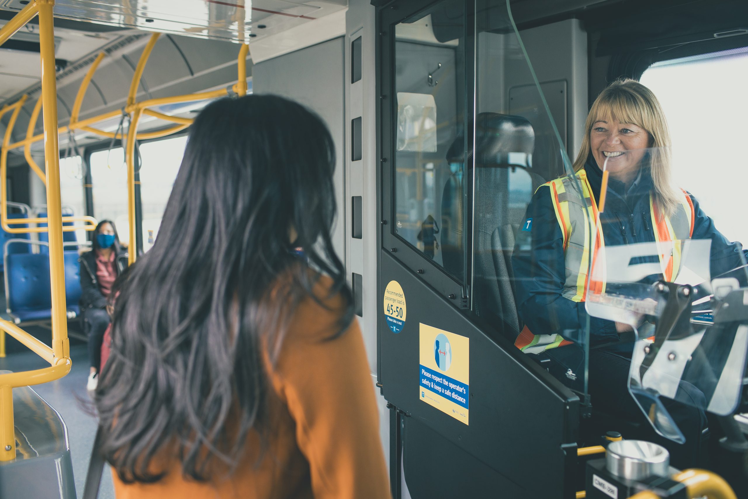 image of a woman getting on a bus with a bus operator smiling at her