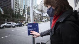 Lynn Jensen feels the braille on the blue bus stop signage