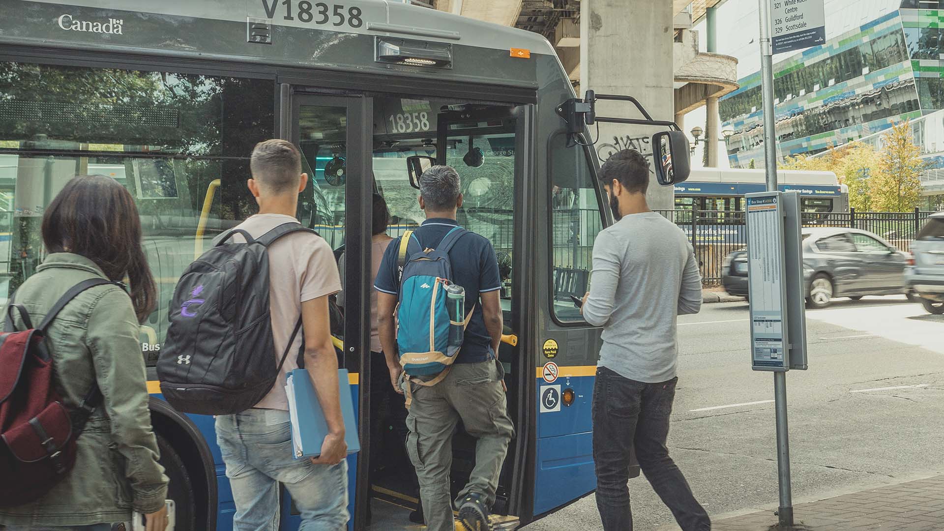 Customers with backpacks boarding the bus at Surrey Central Station