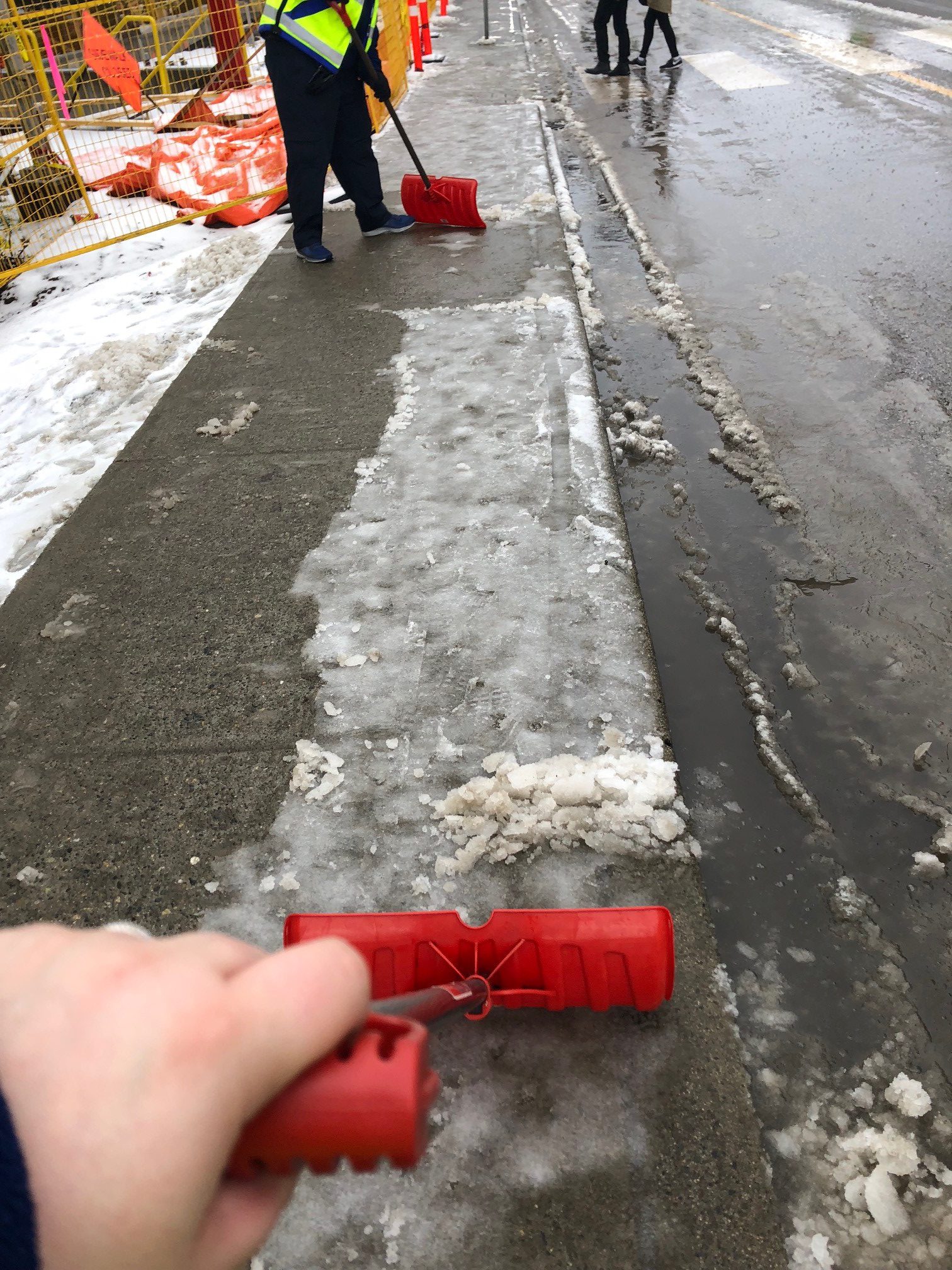SkyTrain Attendants shovelling snow and ice on the sidewalk near 22nd Street Station in 2019