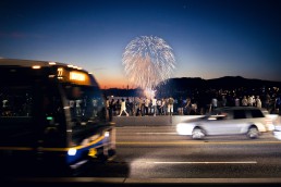 A bus drives by on the Burrard Street bridge as fireworks light up the sky above English Bay