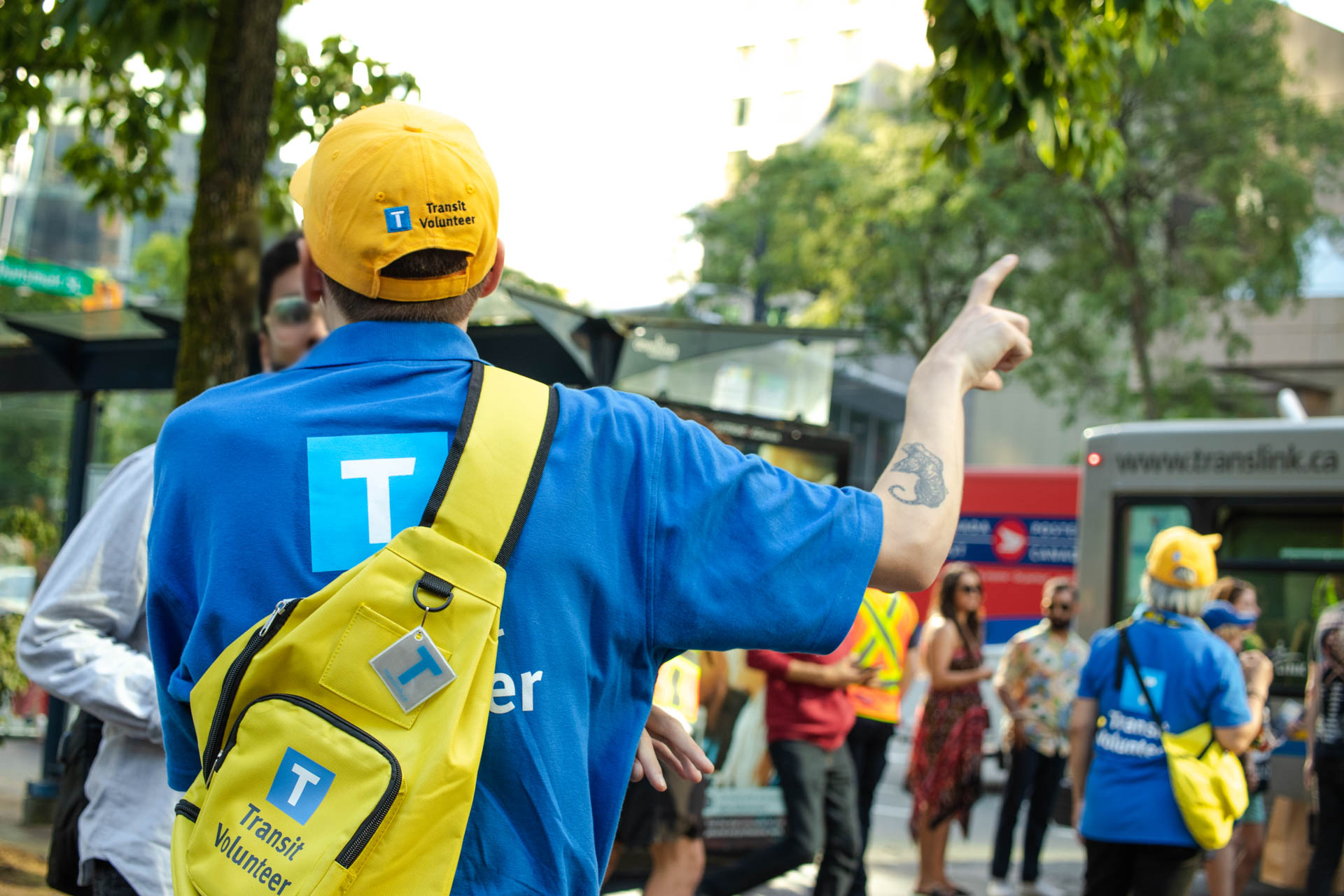 A TransLink Volunteer is shown from the back as he points out directions to a customer