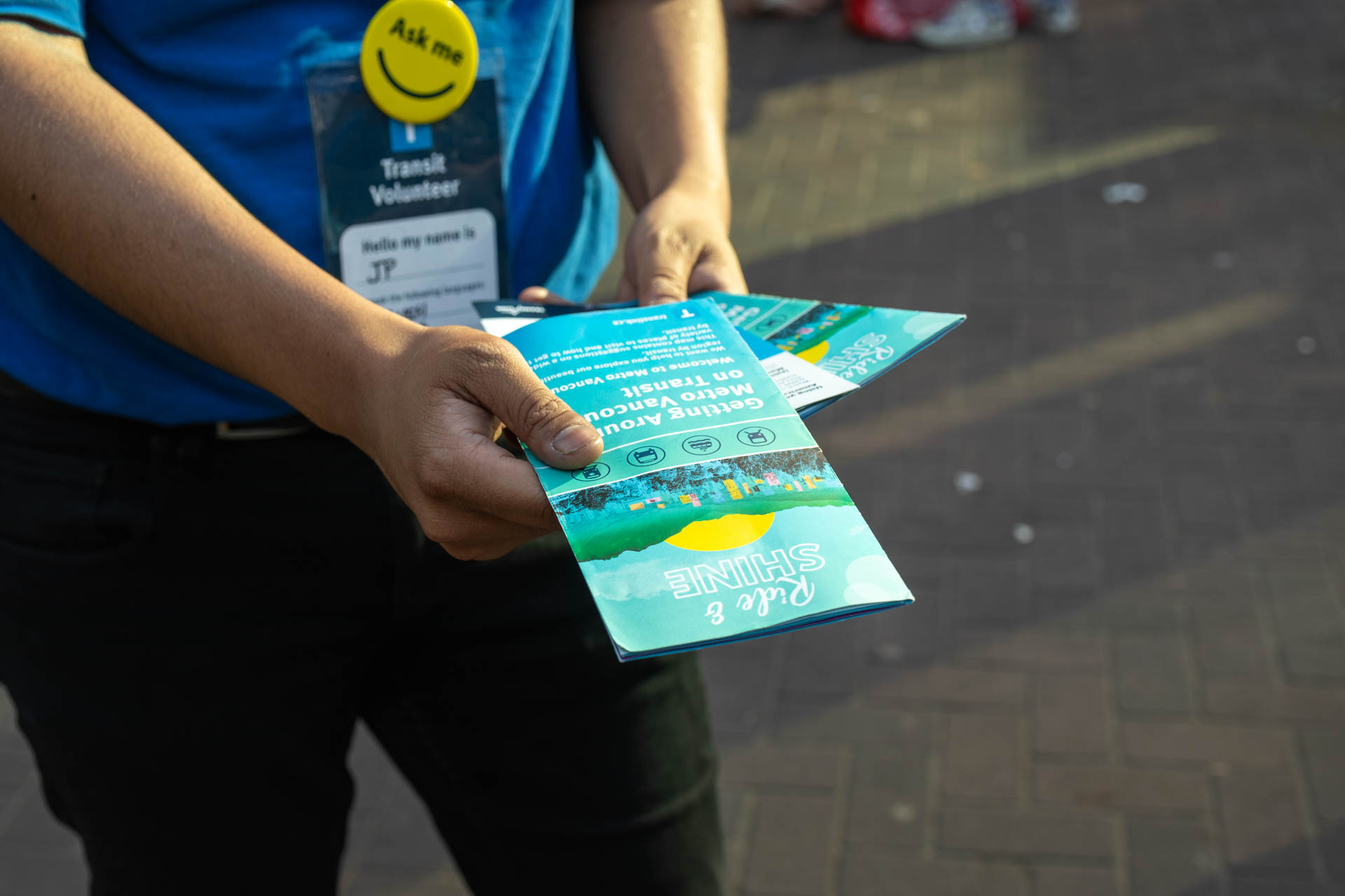 TransLink Volunteer holds out brochure of Ride & Shine campaign