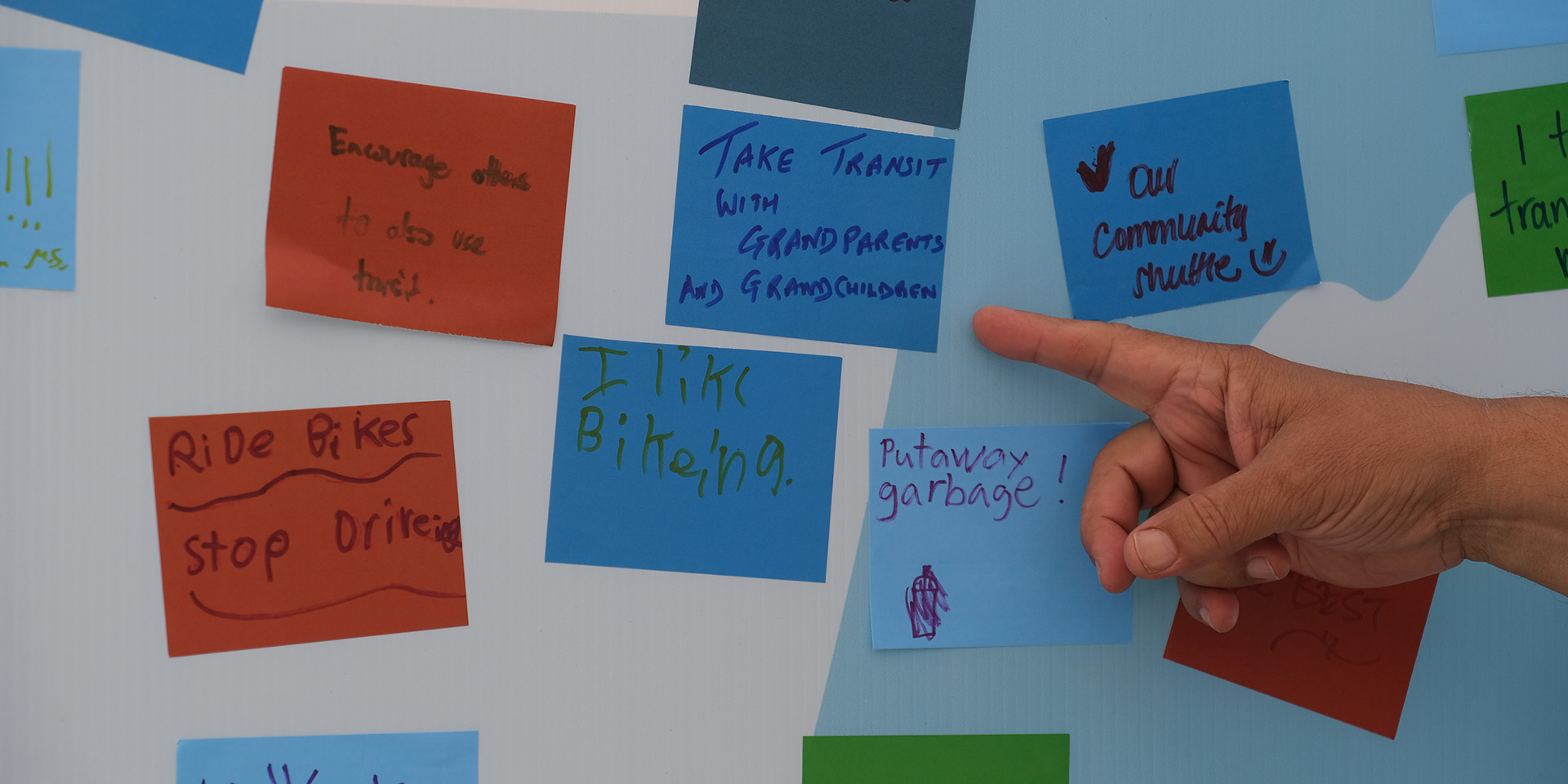 A stick note saying "Take transit with grandparents and grandchildren" on the pledge wall
