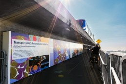 View of Canada Line Bridge murals with SkyTrain passing overhead