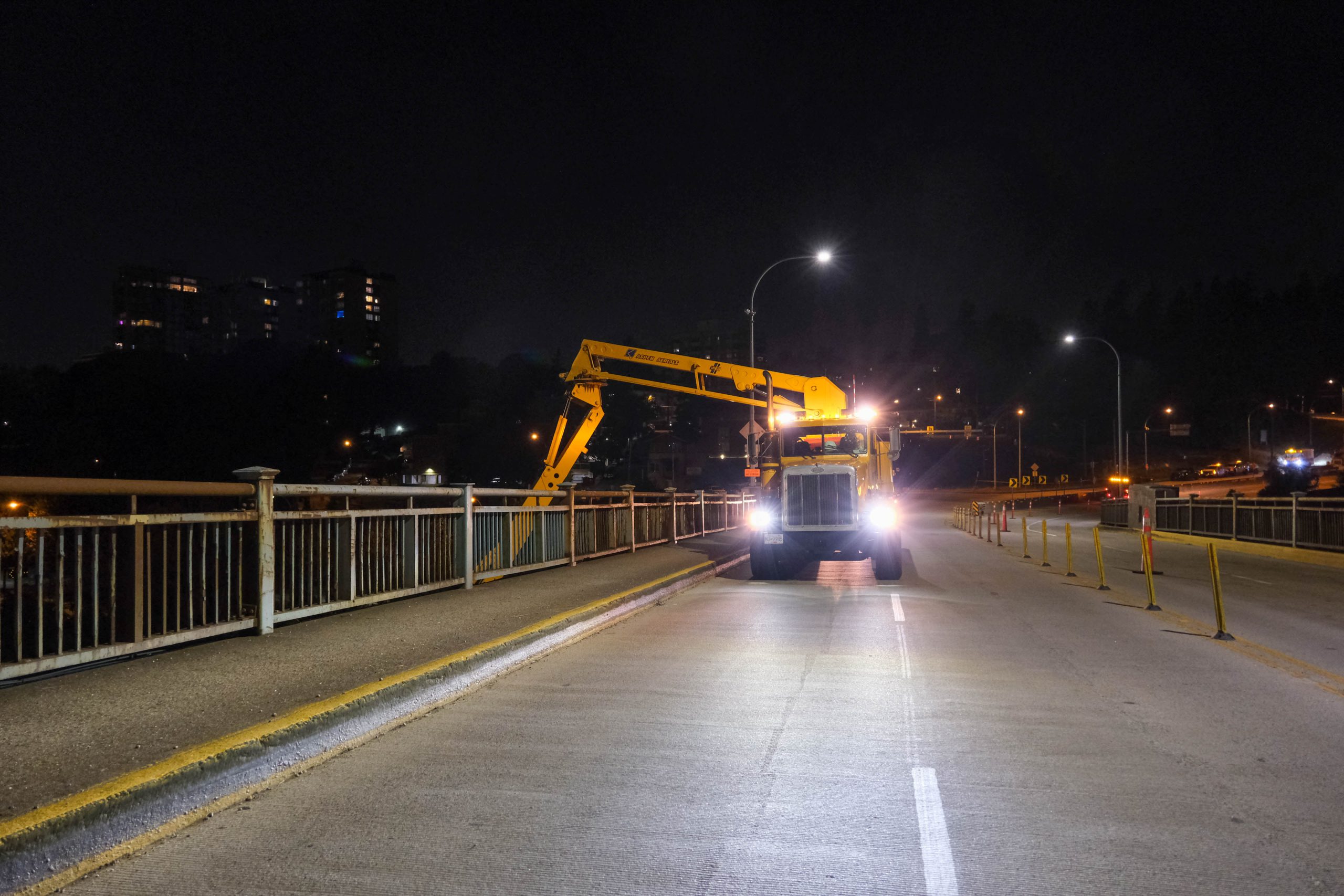 The snooper truck operating on the deck of the Pattullo Bridge at night.