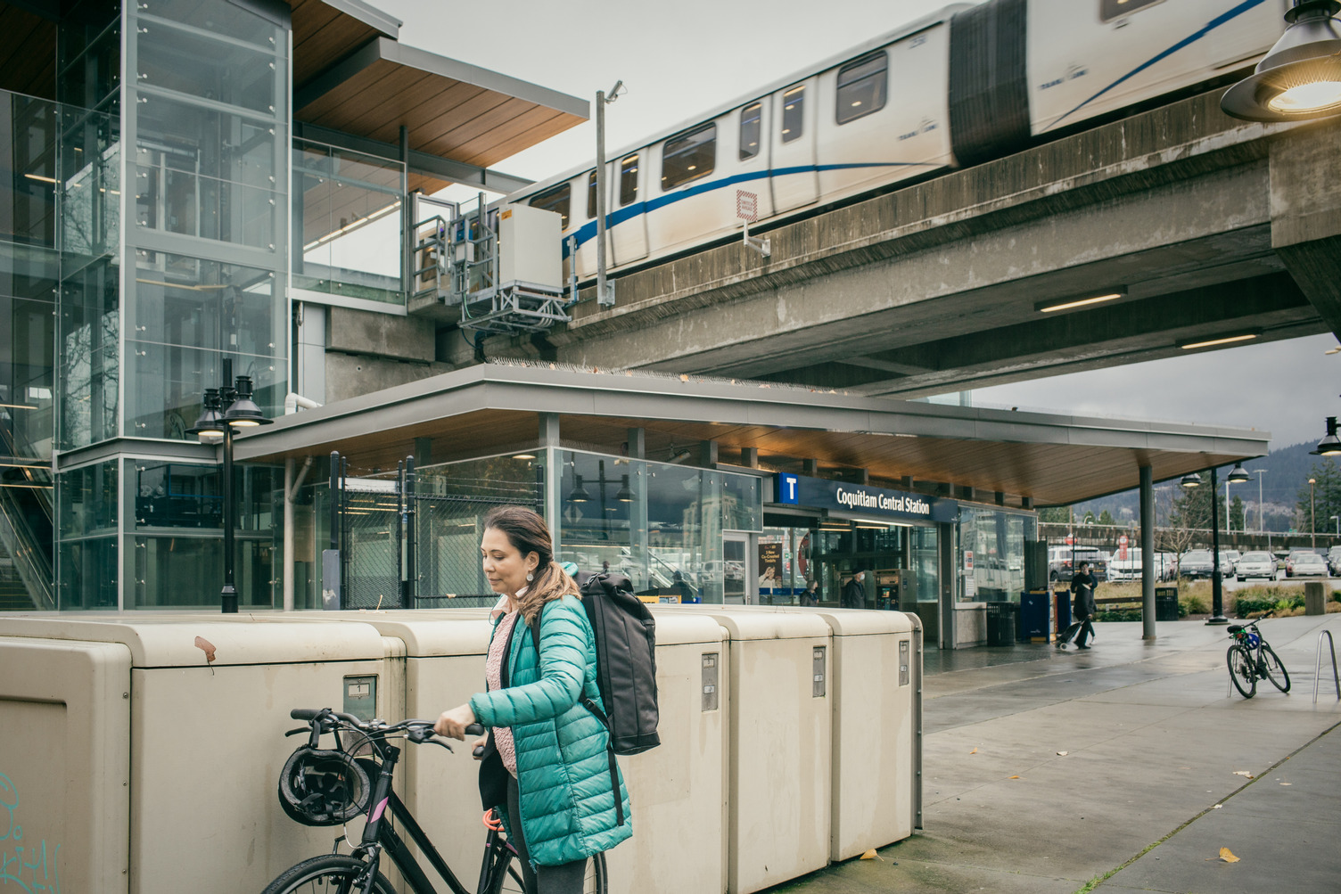 Customer parks bike at locker as SkyTrain car leaves Coquitlam Central Station