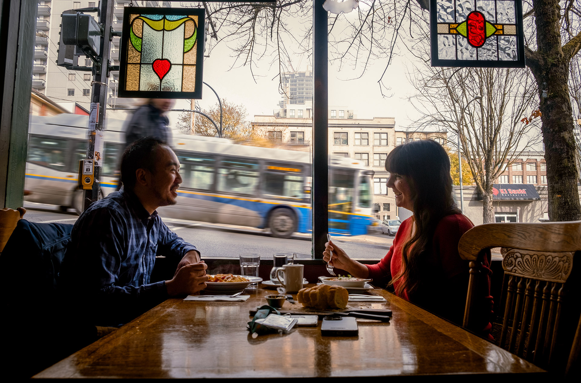 Two people dining at a restaurant as a bus passes by outside
