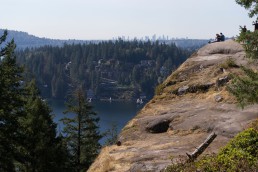 People atop Quarry Rock, overlooking trees and water