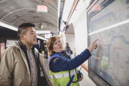 Photo of a SkyTrain attendant working the best jobs in bc assisting a customer using the transit map