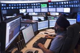 Man at SkyTrain control room, a room filled with monitors