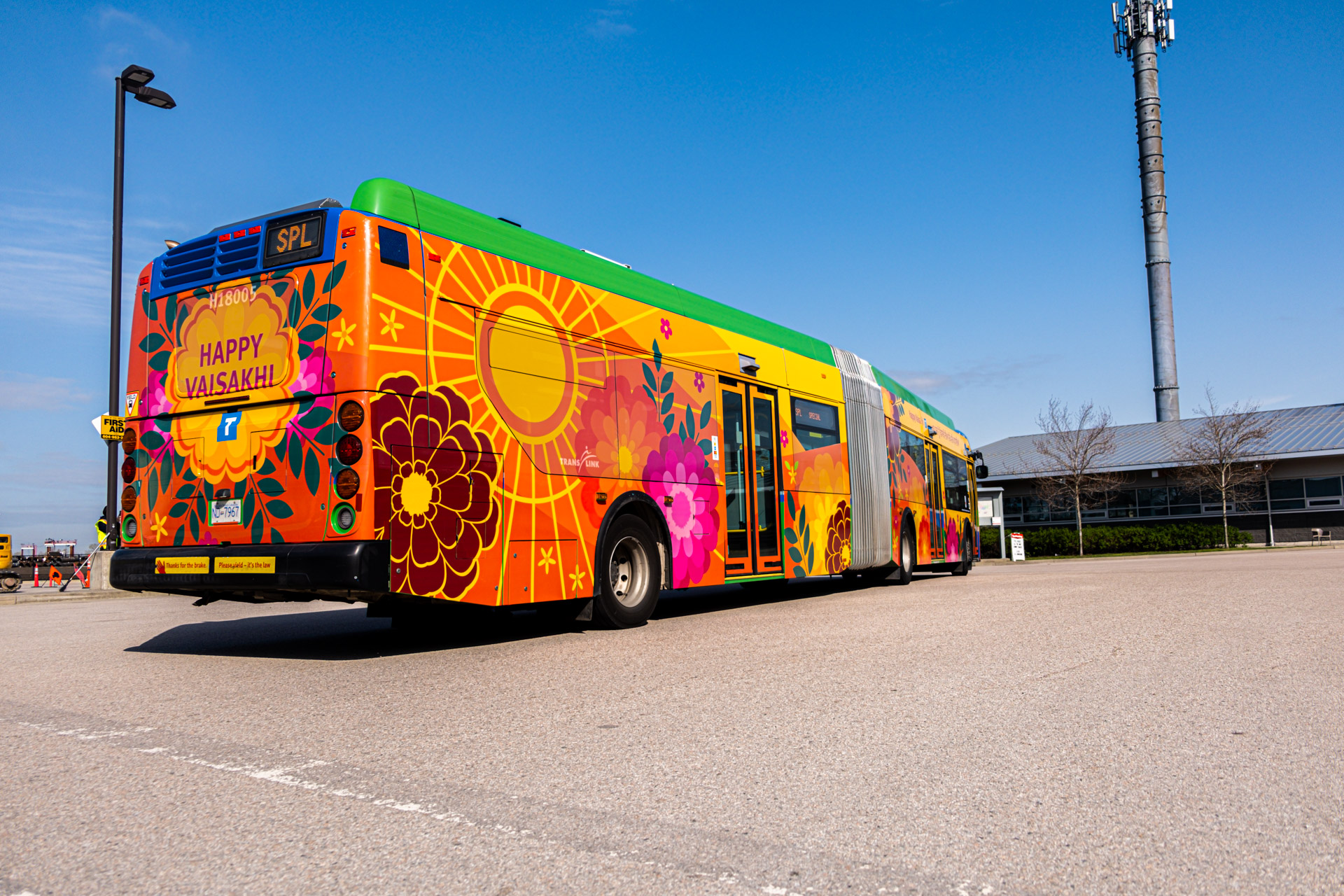 a RapidBus sits parked at Hamilton Transit Centre, wrapped in a colourful Vaisakhi design for the Vancouver Vaisakhi parade and Surrey Vaisakhi parade.
