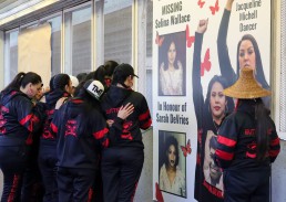 Photo of Butterflies in spirit dancers looking at the MMIW art installation at Stadium–Chinatown Station