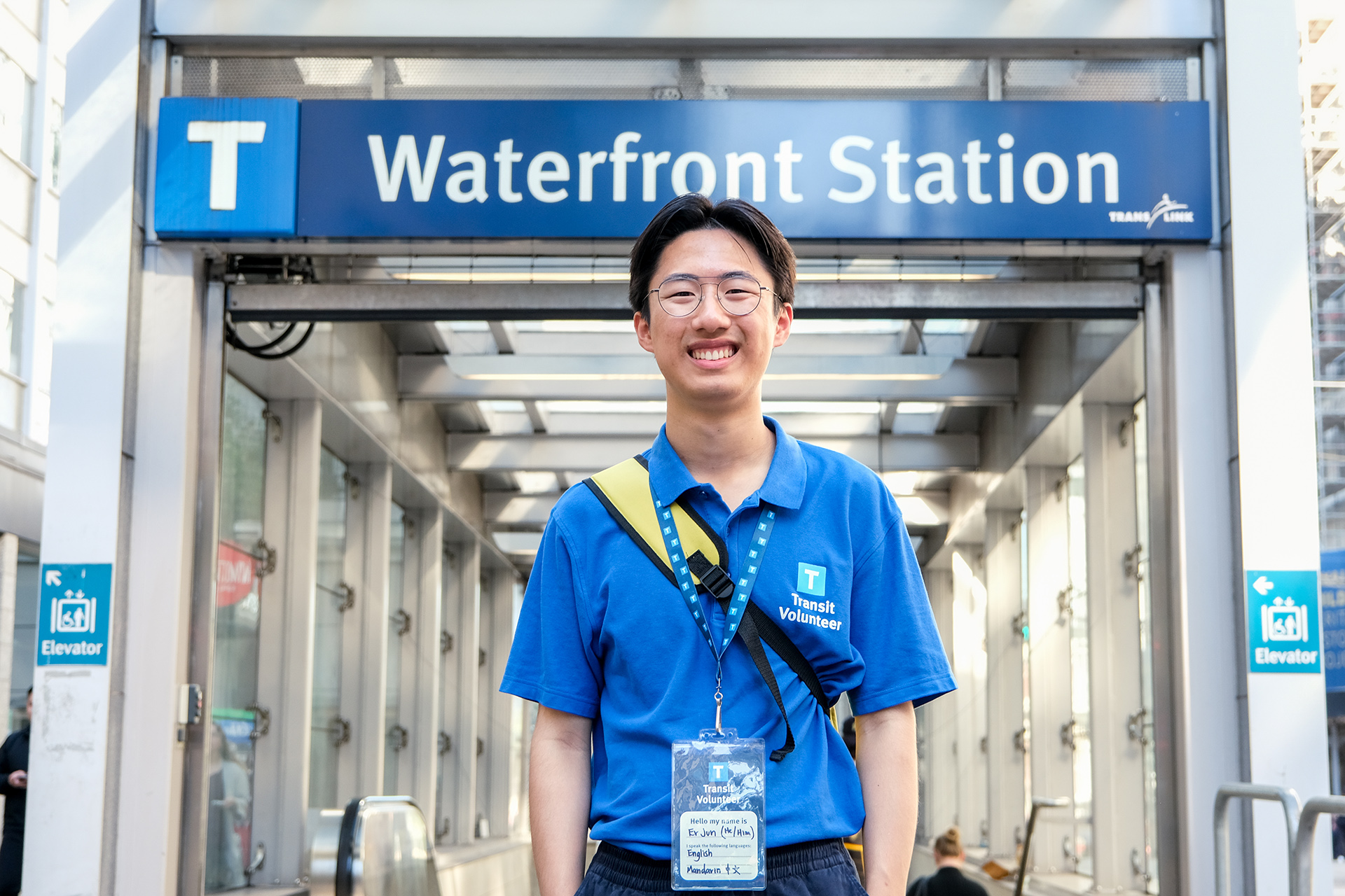 Community Transit Volunteer Er Jun Ma standing behind a Waterfront Station entrance