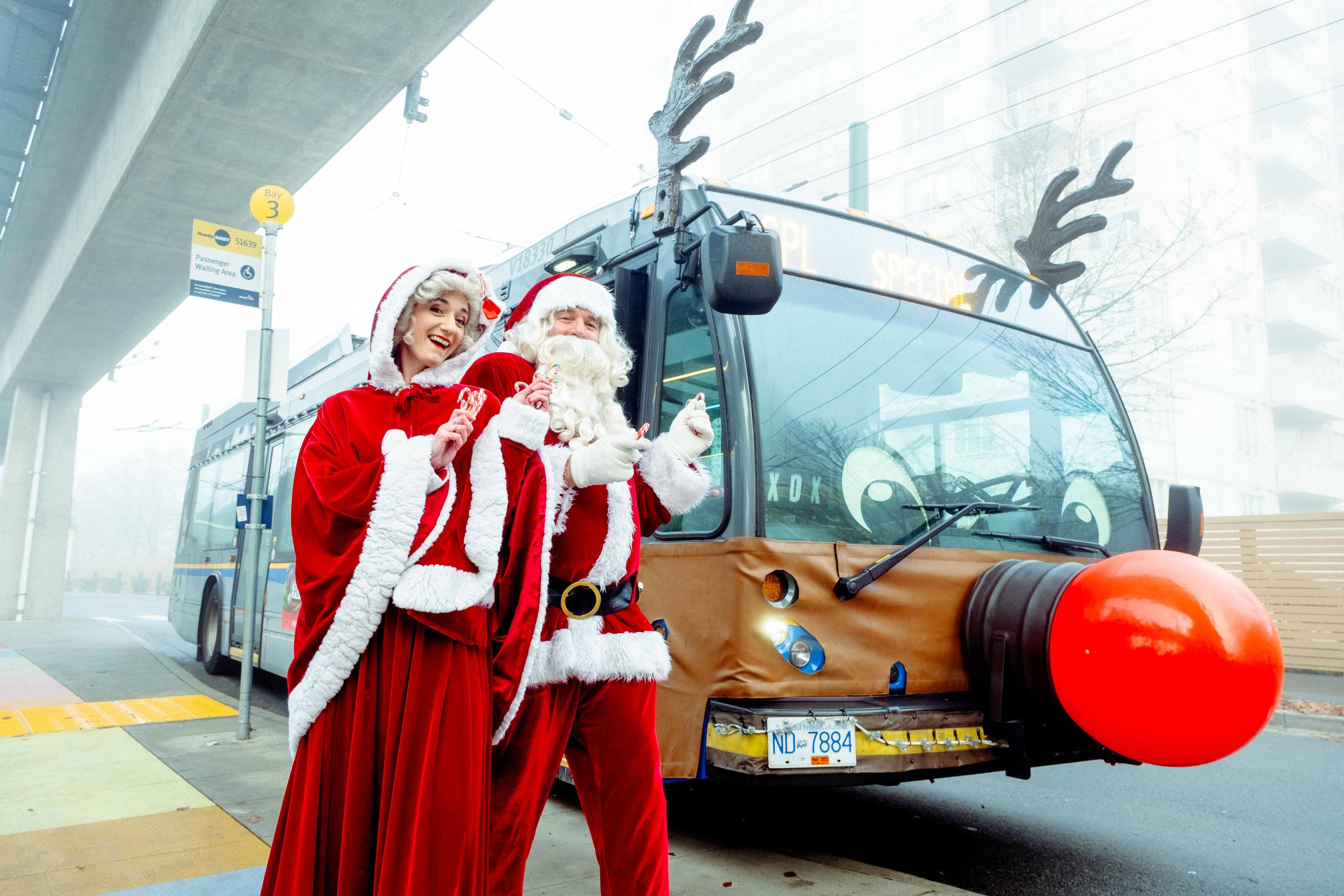 Mr. and Mrs. Claus in front of the Reindeer Bus