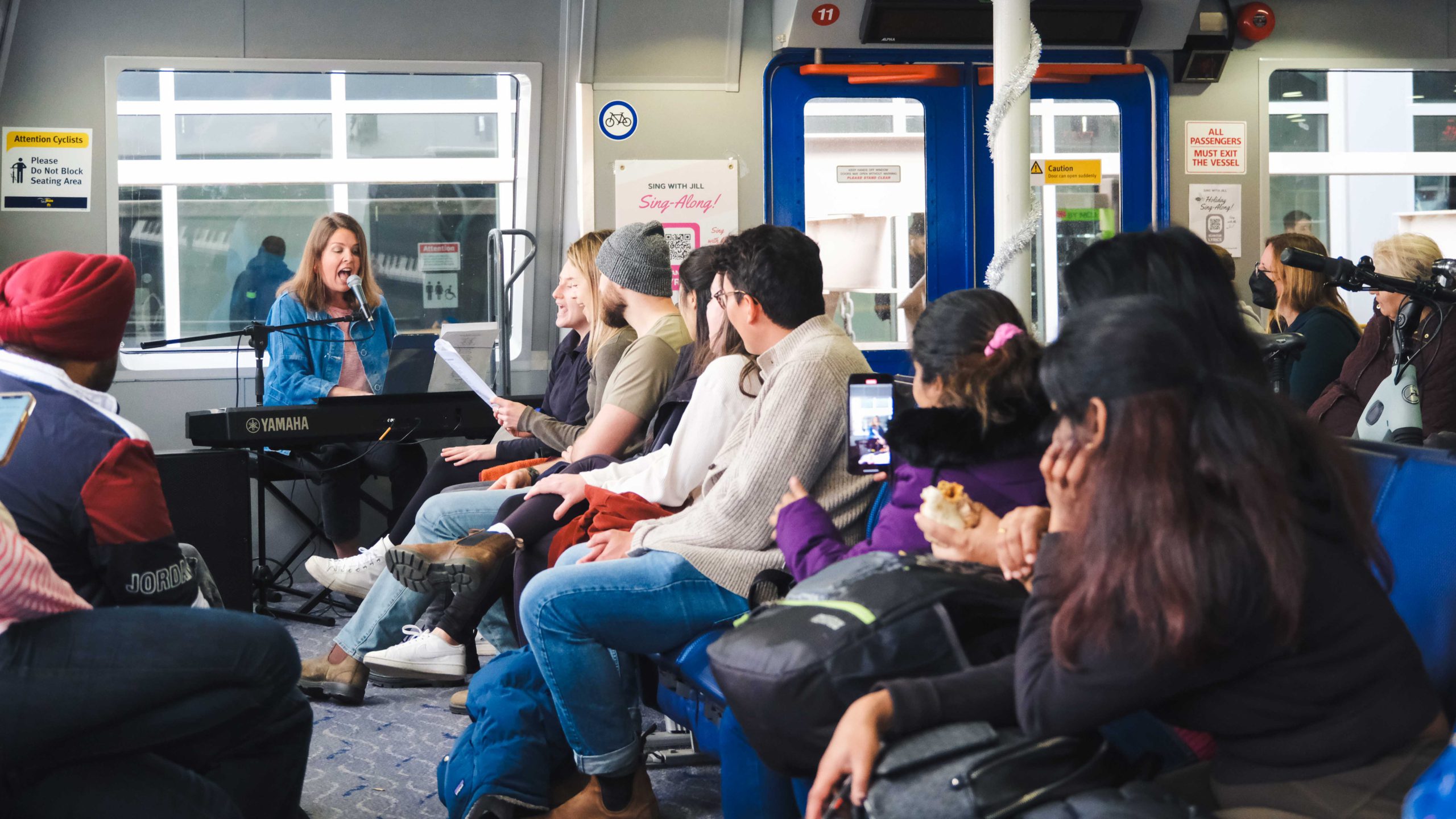 Commuters sing with vocalist and singer, Jill, on the SeaBus during a sing-along.