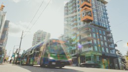 A R5 Hastings St RapidBus passes by a residential tower on Hastings Street