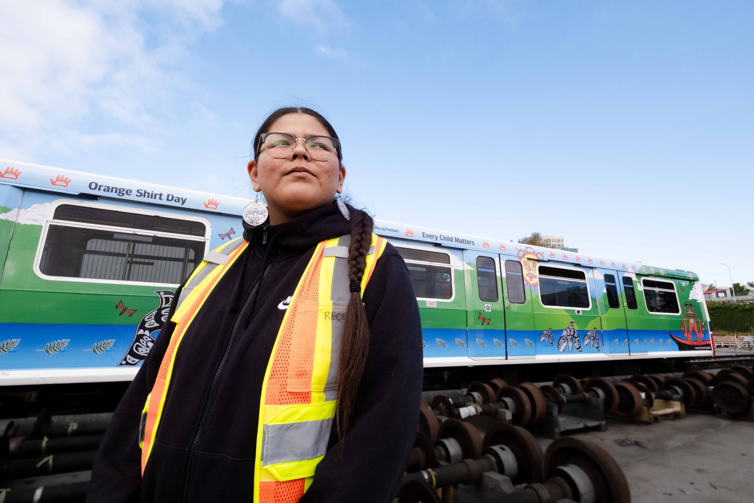 Artist Shonta Campbell stands in front of the SkyTrain car wrapped with her art