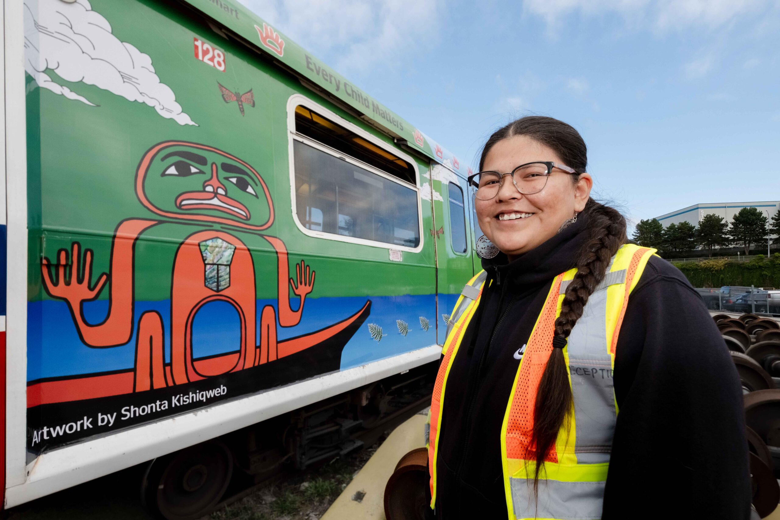 Artist Shonta Campbell stands in front of the SkyTrain car wrapped with her art