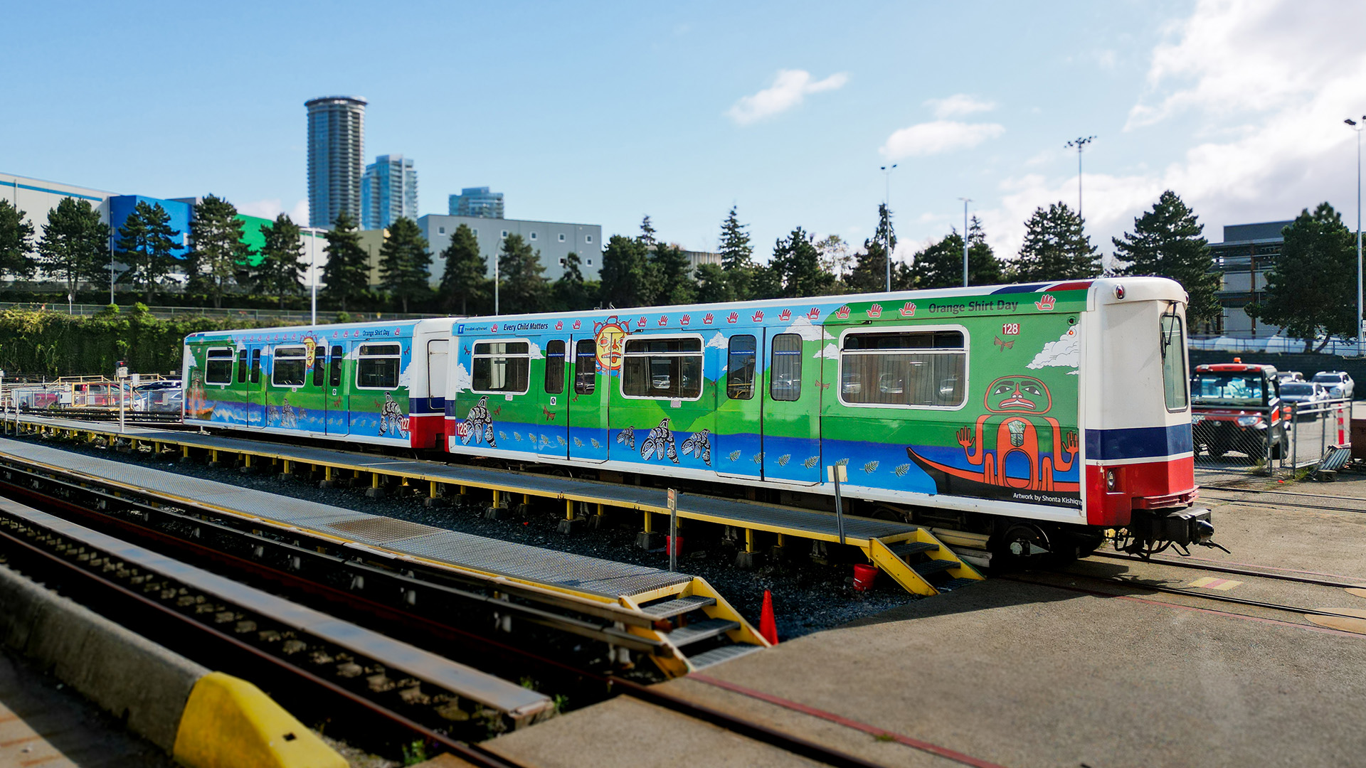 Artist Shonta Campbell stands in front of the SkyTrain car wrapped with her art