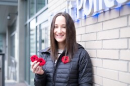 Woman stands in front of Transit Police HQ with poppies