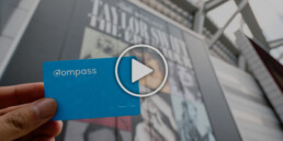 A person holding up a Compass Card at BC Place with a play button on the image