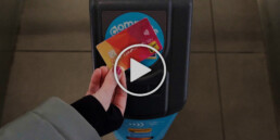 A contactless debit card tapping on a Compass faregate with a play button