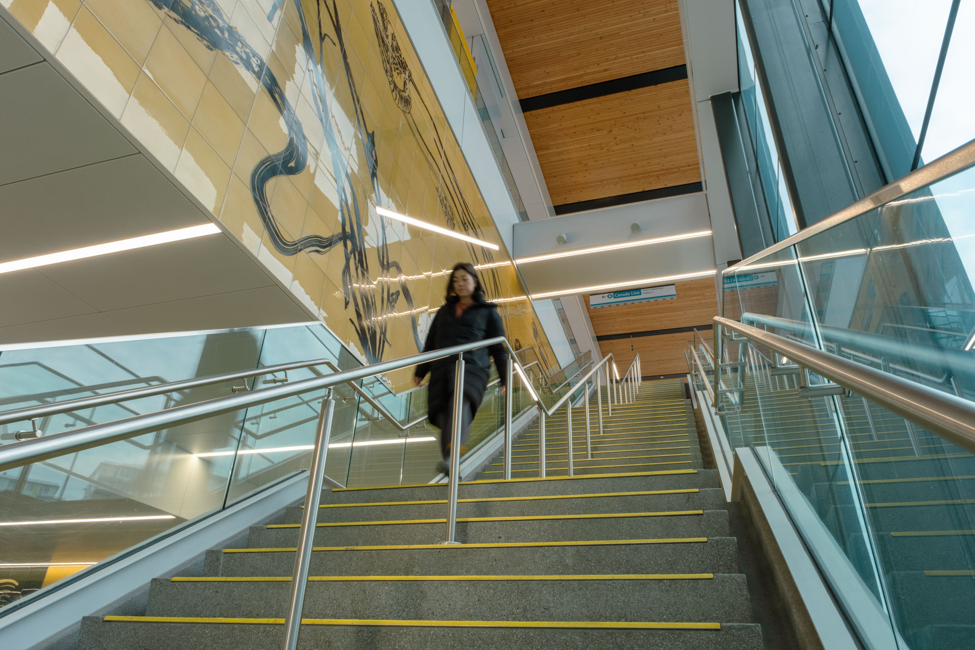 A person walking down the stairs at Capstan Station, past the public art.