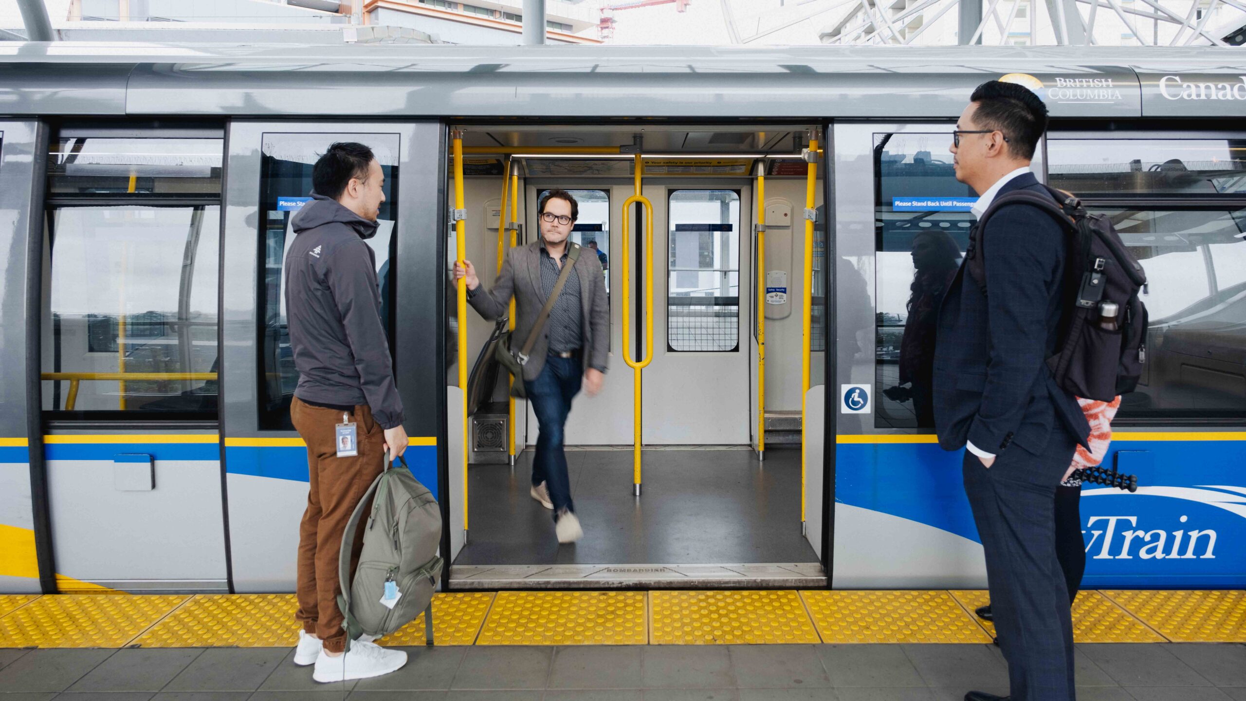 passengers use proper transit etiquette and wait to board a SkyTrain as the doors open to let another customer out