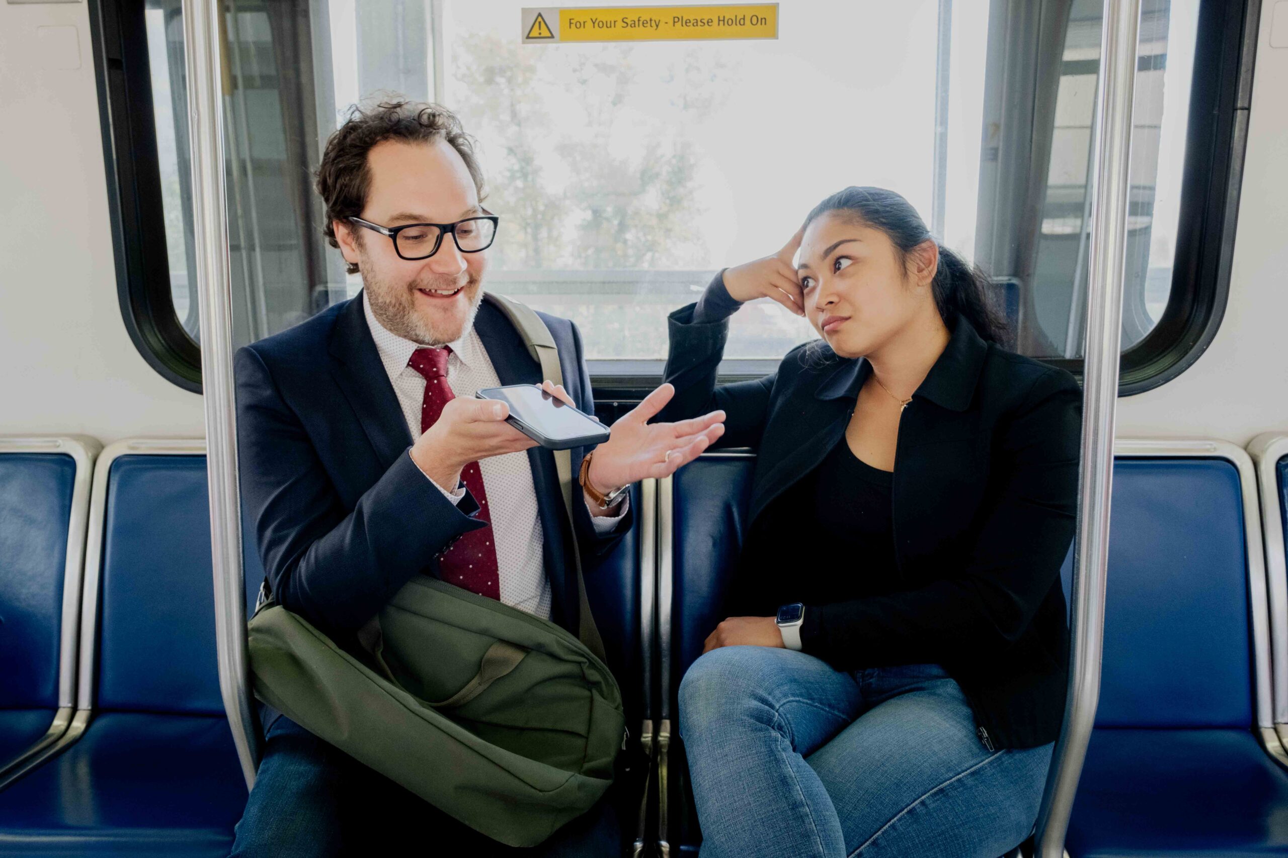 A customer talks loudly on speakerphone while another customer looks annoyed at the lack of transit etiquette