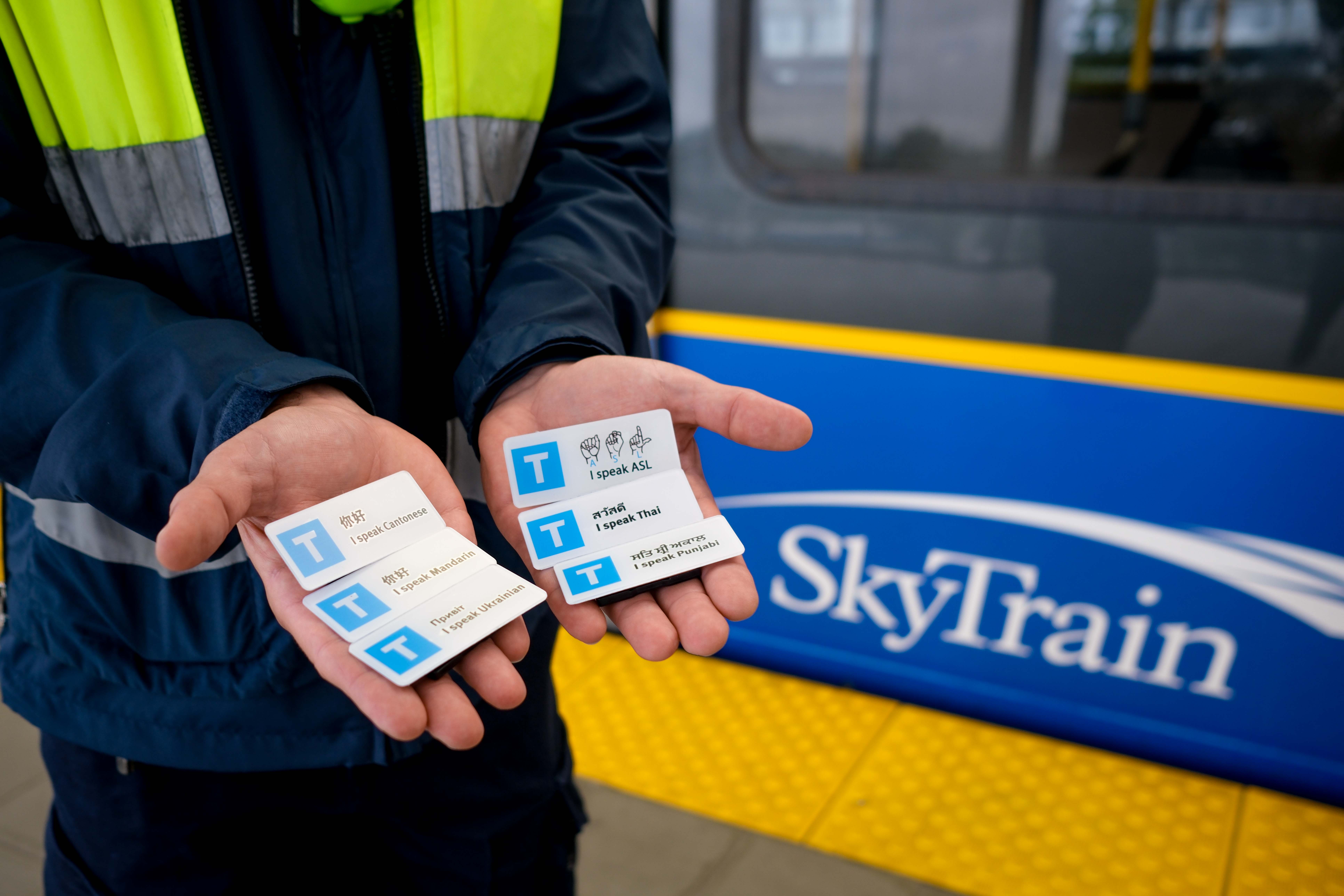 SkyTrain Attendant holds up language pins outside of a SkyTrain