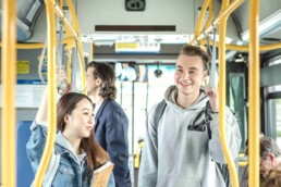 Two students hold onto the bus while travelling to class