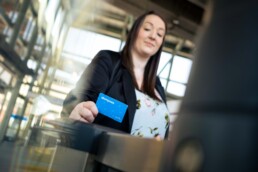 A woman holds a Compass Card to the fare gates