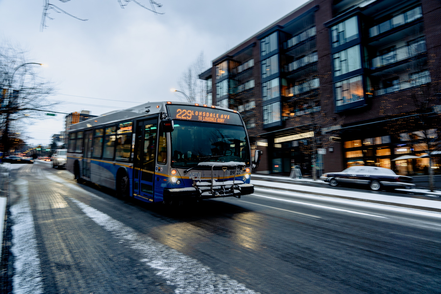 229 bus drives down Lonsdale in the winter with snow on the road