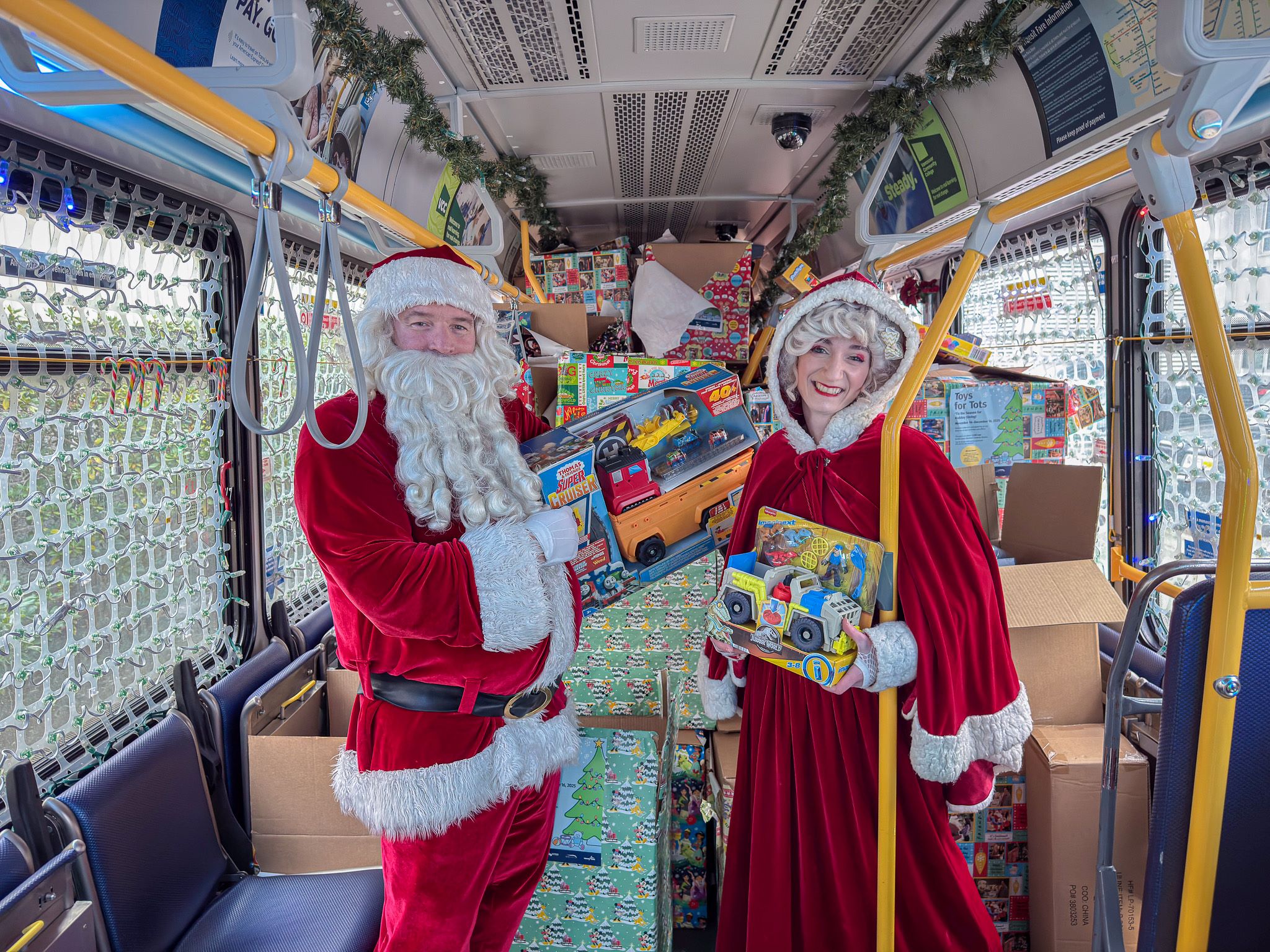 Santa and Mrs. Claus pose for photo in the Reindeer Bus while picking up Toys for Tots