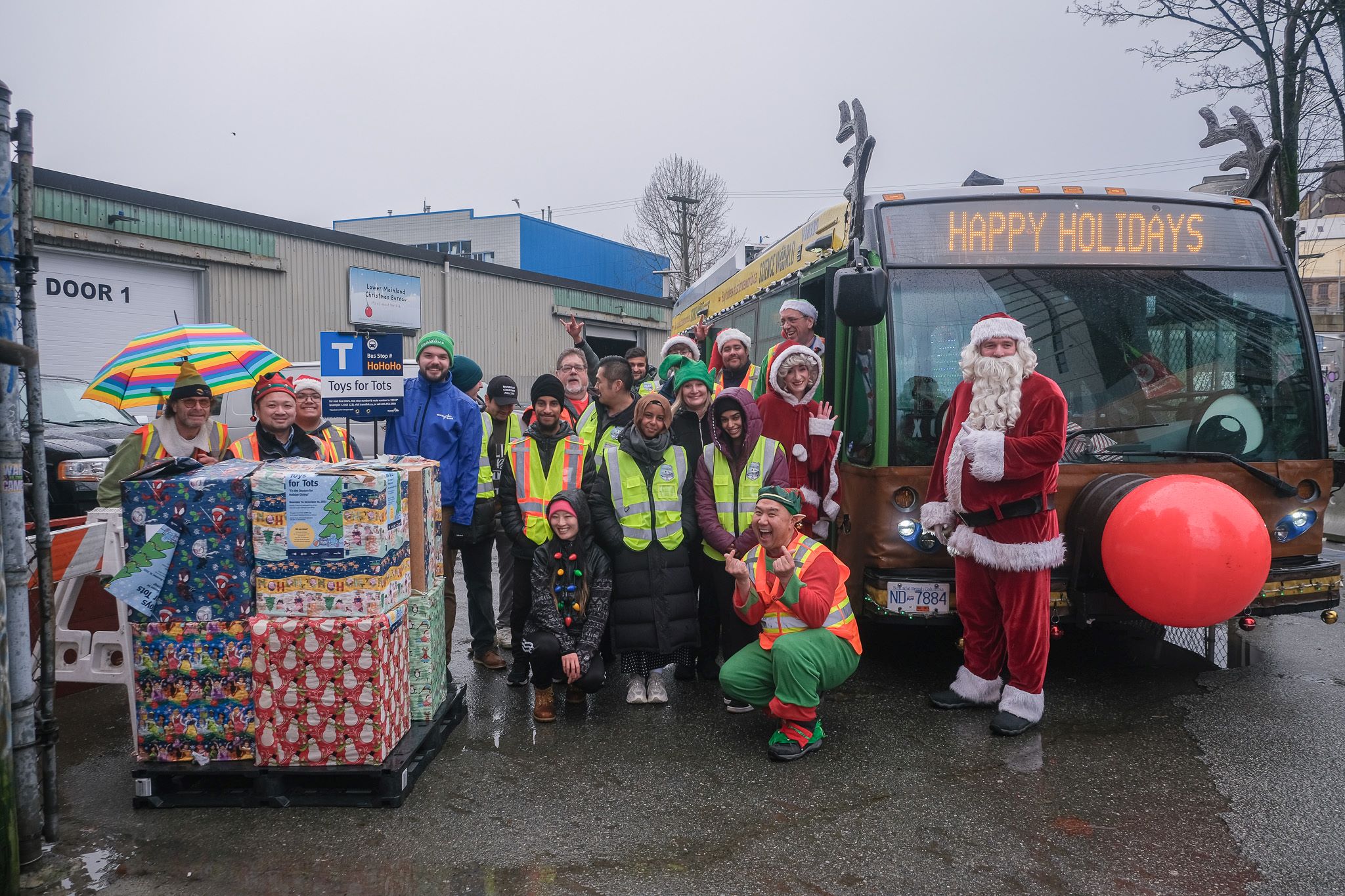 Staff and volunteers pose for photo in front of the Reindeer Bus while dropping of Toys for Tots at the Lower Mainland Christmas Bureau