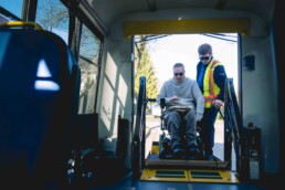 HandyDART client Brian Gibney uses the lift on the bus with the help of operator