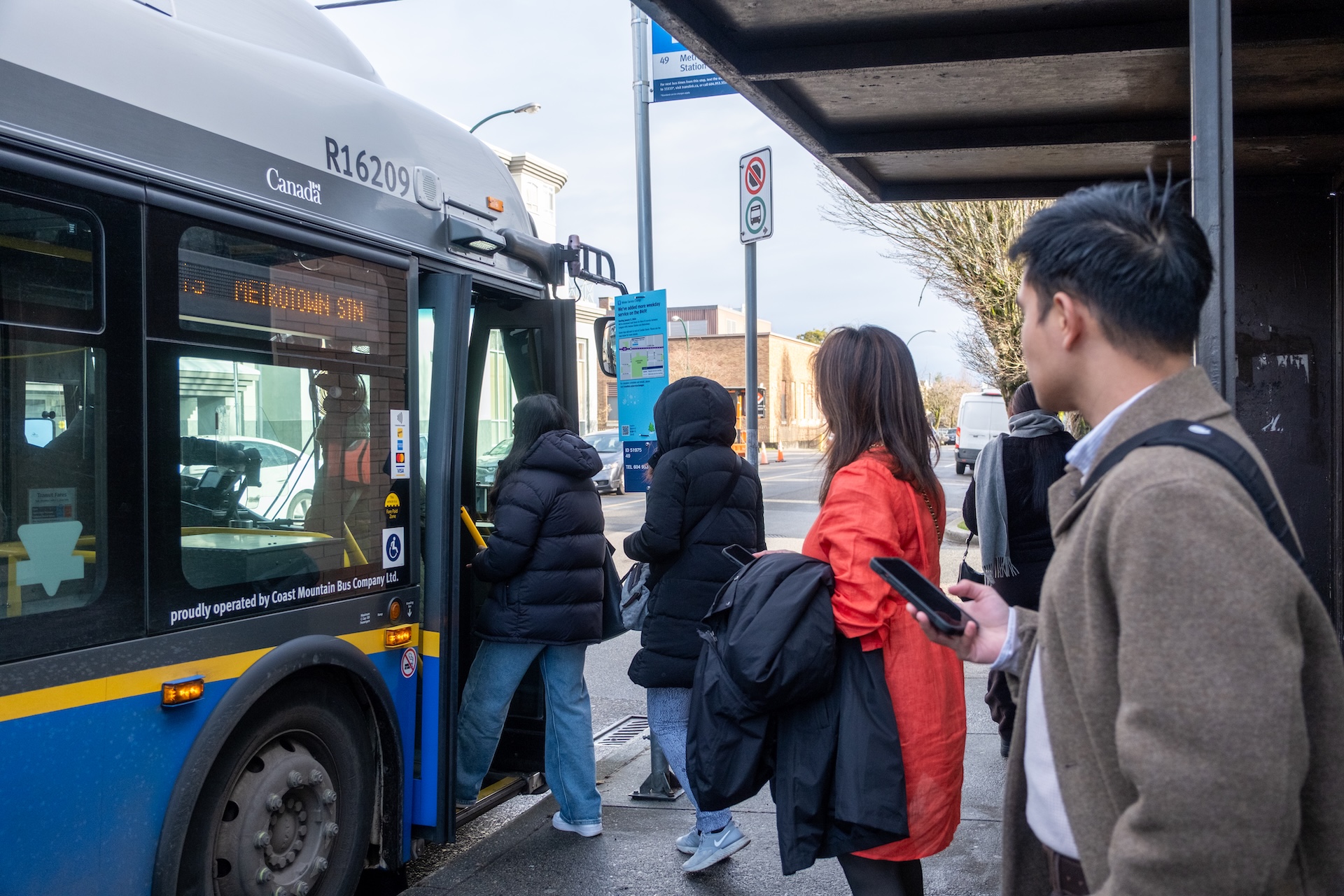Passengers board the 49 Metrotown Station bus at the Knight Street stop, while others wait under the bus shelter.