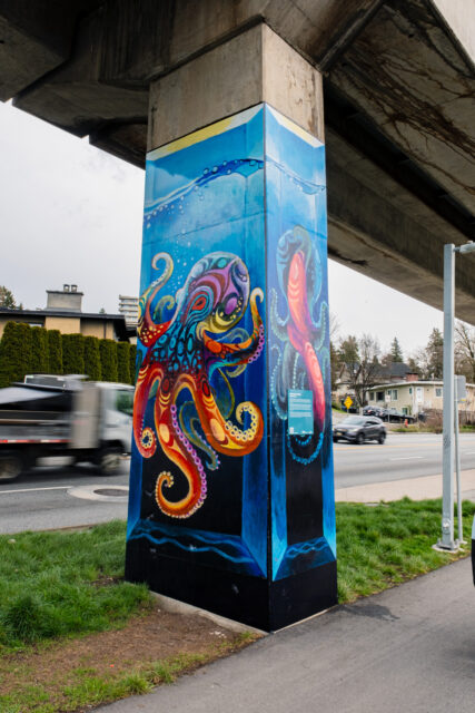“Octopus Sxweli” by Brandon Gabriel, a SkyTrain pillar artwork depicting a vividly coloured octopus surrounded by blue, water‑inspired forms.