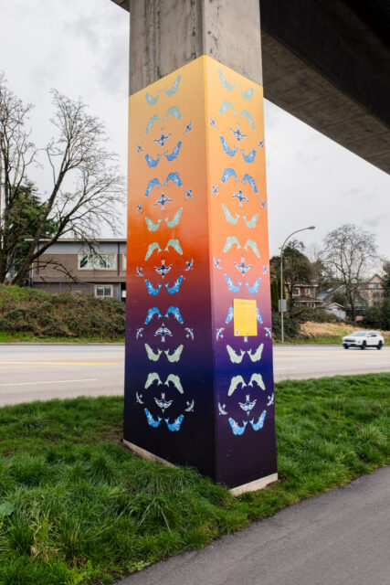 “Swimming and Flight, Movement in Sight” by Natache Gabriel, a SkyTrain pillar artwork showing salmon and sparrows arranged in vertical patterns, symbolizing land and water life.